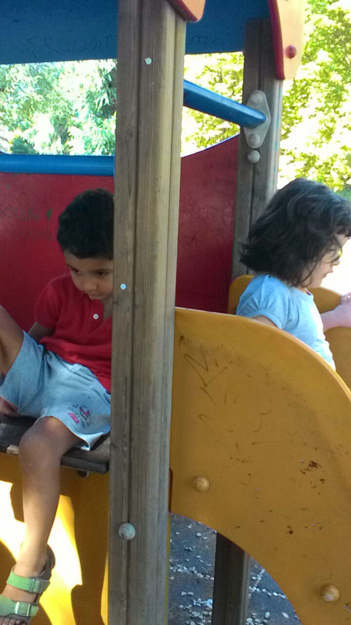 Un'immagine che ritrae attrezzature da gioco all'aperto, spazio pubblico, ricreazione, scivolo da parco giochi e bambino.