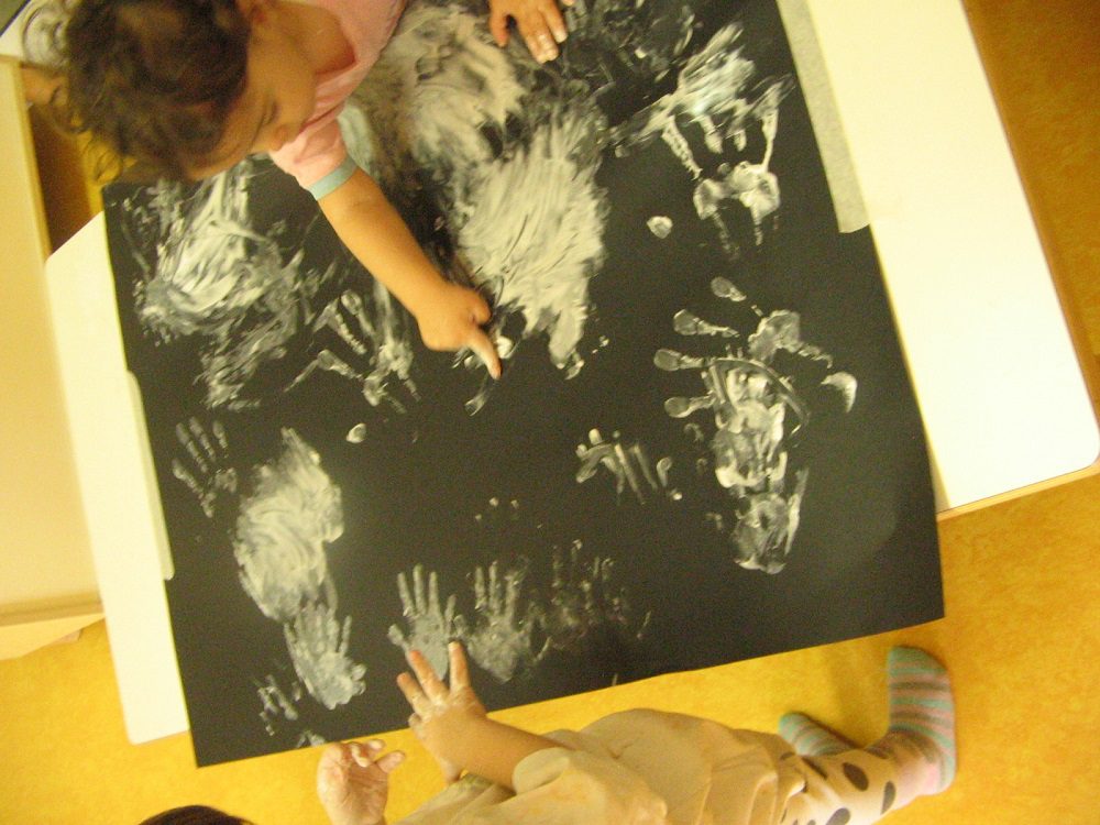 Un'immagine che ritrae mano, bambino, carta, bambino che fa i primi passi e colore.