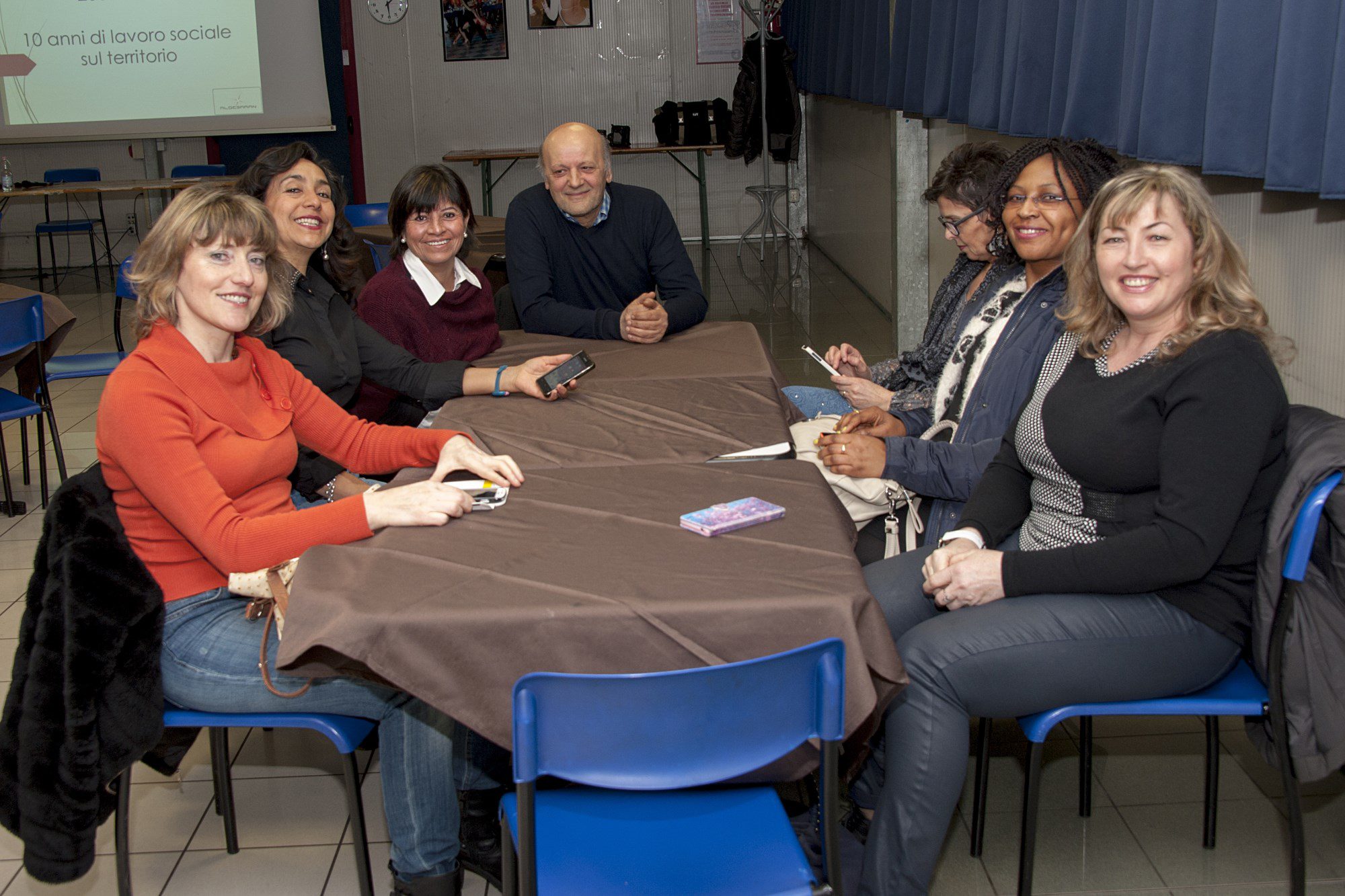 Un'immagine che ritrae mobilia, sedia, jeans, capispalla e gruppo sociale.