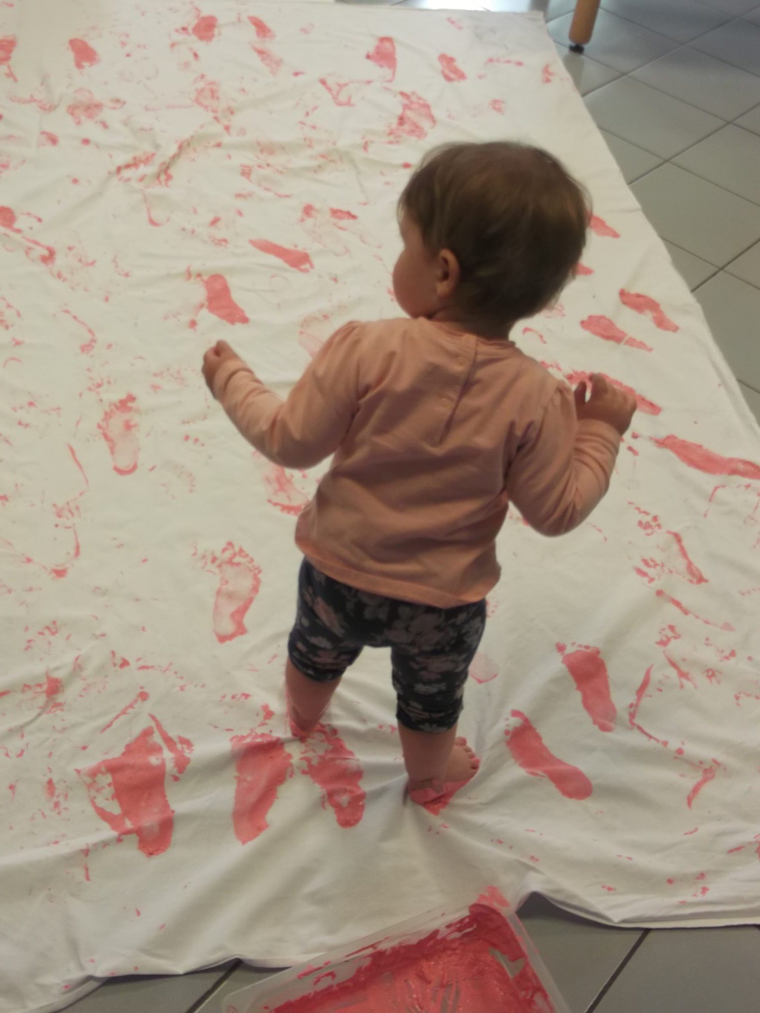 Un'immagine che ritrae bambino, pavimentazione, abbigliamento per neonati e bambini piccoli, pavimento e bambino che fa i primi passi.