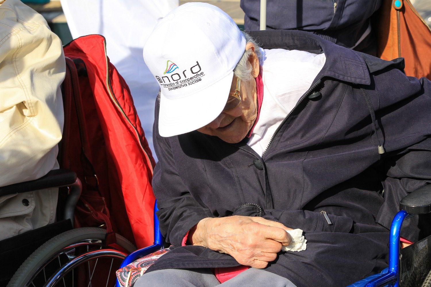 Un'immagine che ritrae sedia a rotelle, cappello, berretto, seduta e berretto da baseball.