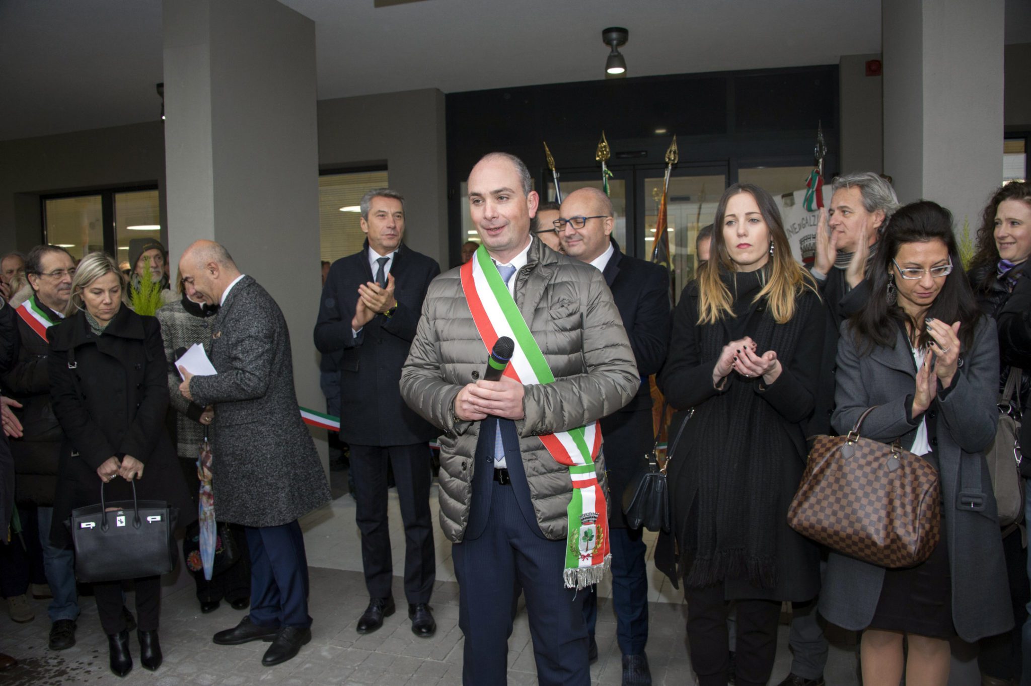 Un'immagine che ritrae capispalla, in piedi, cappotto, abito e impiegato.
