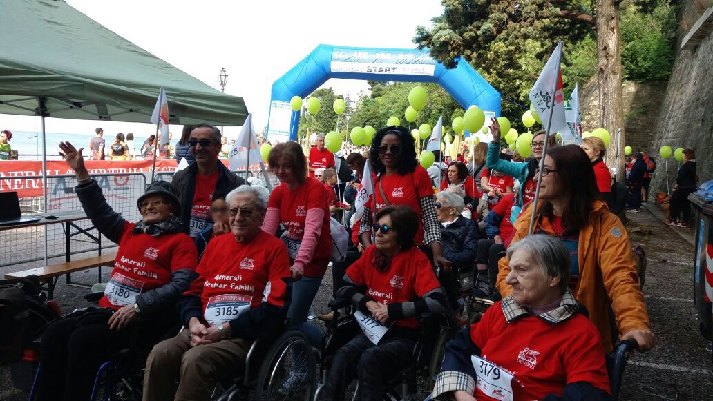 Un'immagine che ritrae sedia a rotelle, pantaloni, gruppo sociale, sorriso e comunità.