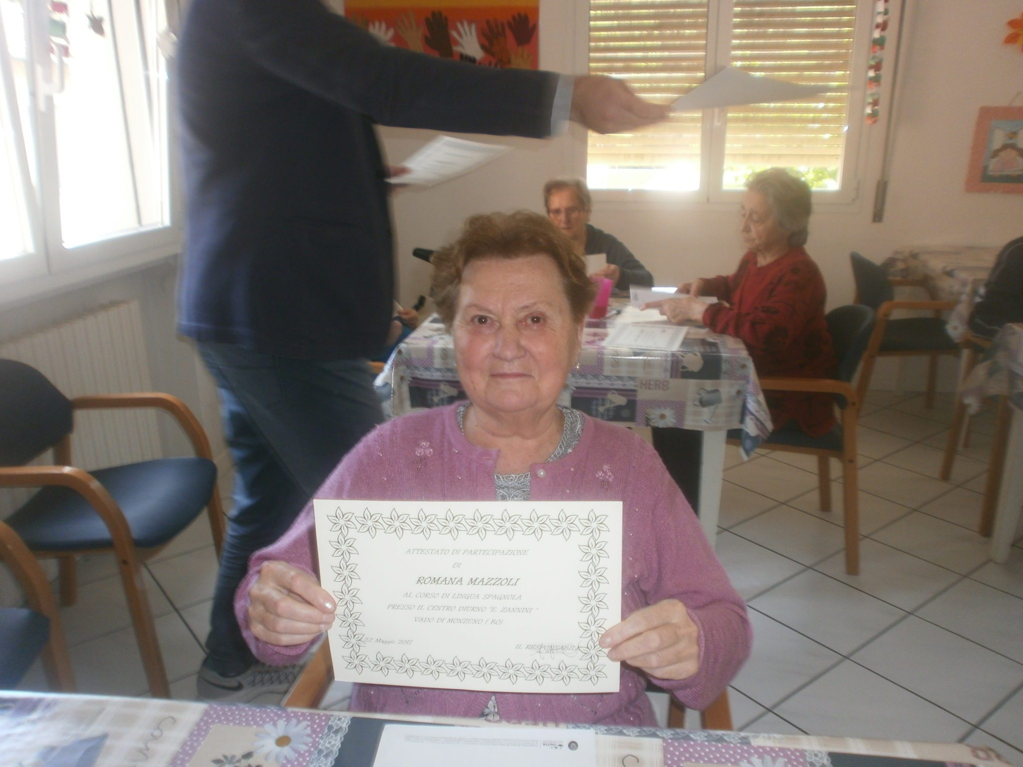 Un'immagine che ritrae mobilia, sorriso, sedia, tovaglia e nonno.