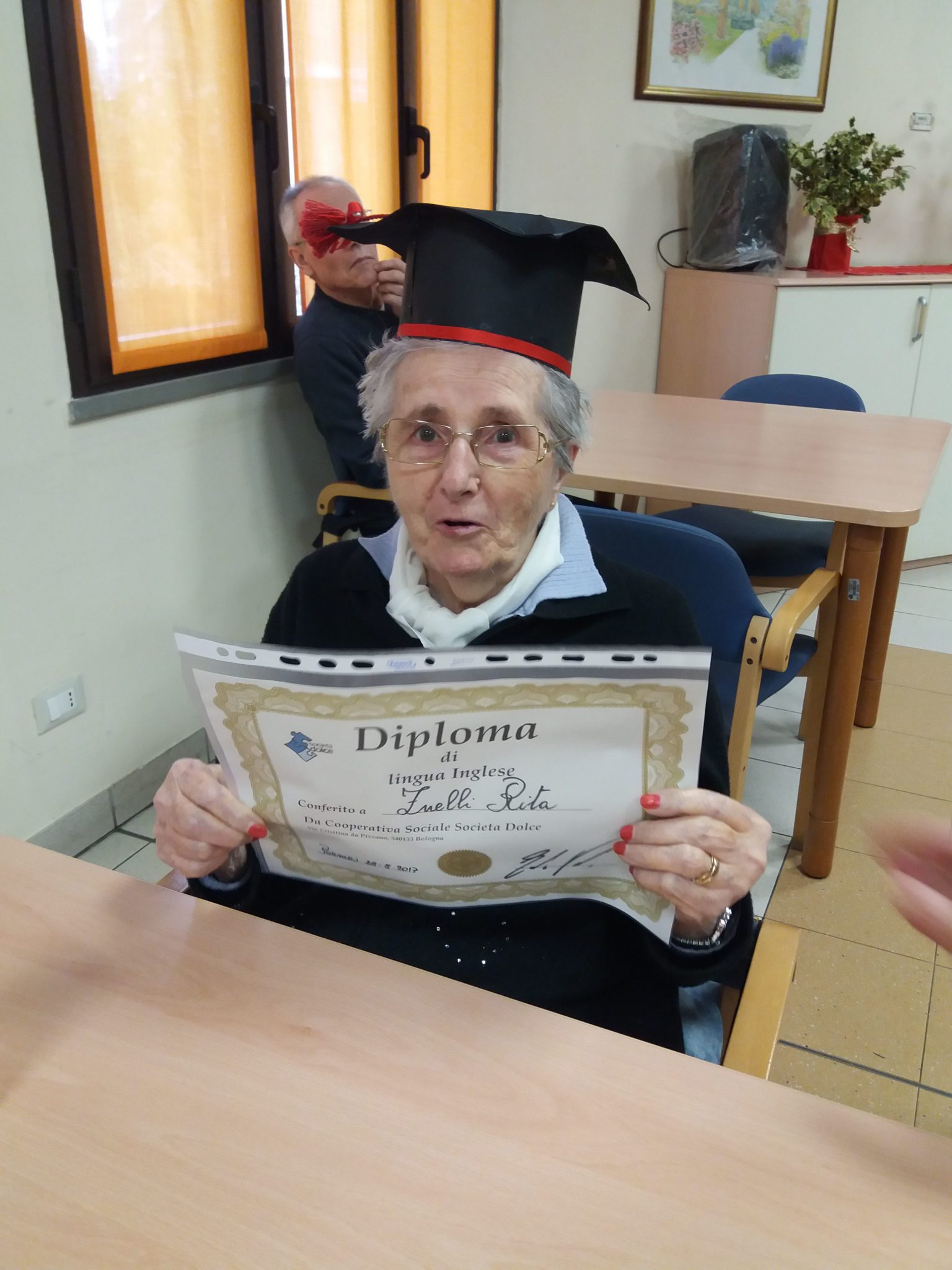 Un'immagine che ritrae sorriso, studioso, abito accademico, cappello accademico quadrato e cornice.