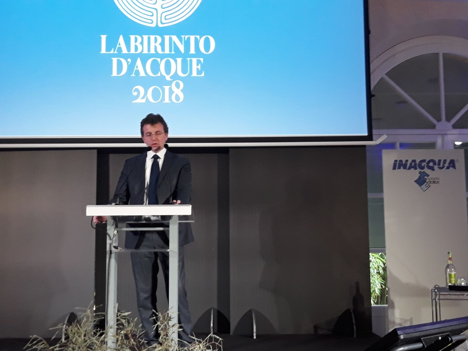 Un'immagine che ritrae apparecchiature audio, dispositivo elettronico, podio, leggio e portavoce.