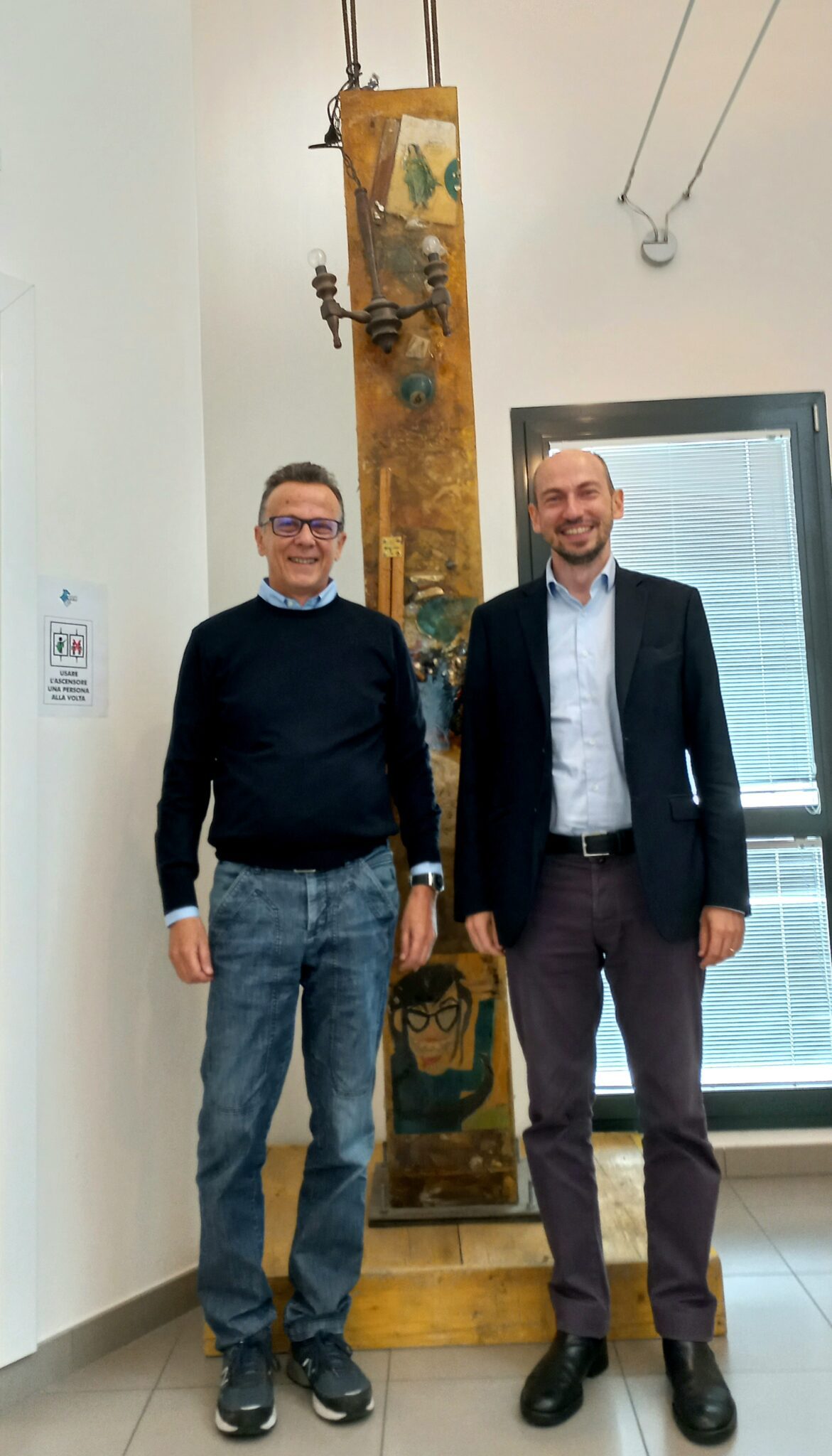 Un'immagine che ritrae in piedi, impiegato, blazer, pantaloni da abito e mostra.
